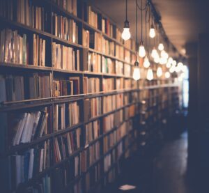 Cozy library or bookstore interior with tall bookshelves filled with books and warm hanging Edison light bulbs creating a soft, ambient atmosphere